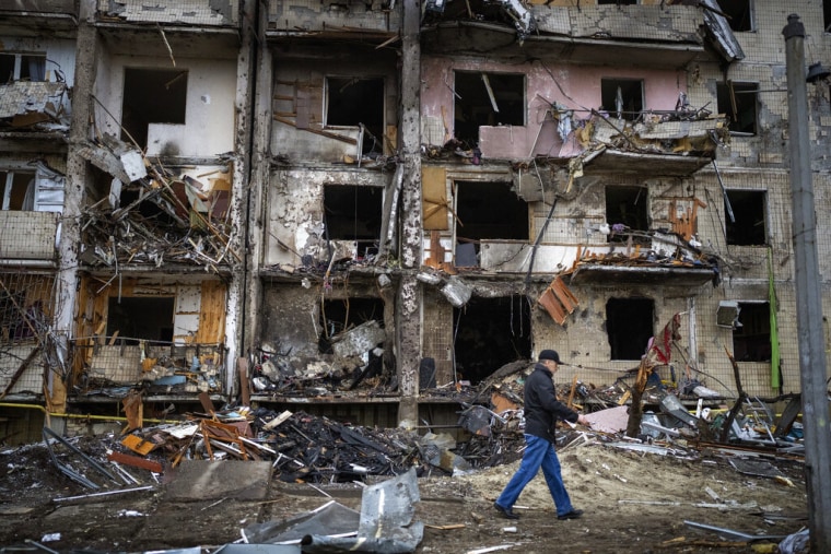 Un hombre pasa por delante de un edificio dañado por el impacto de un proyectil, en Kiev, Ucrania, el 25 de febrero de 2022.