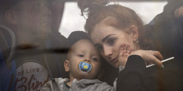 A woman holds her baby inside a bus as they leave Kyiv, Ukraine, on Feb. 24.