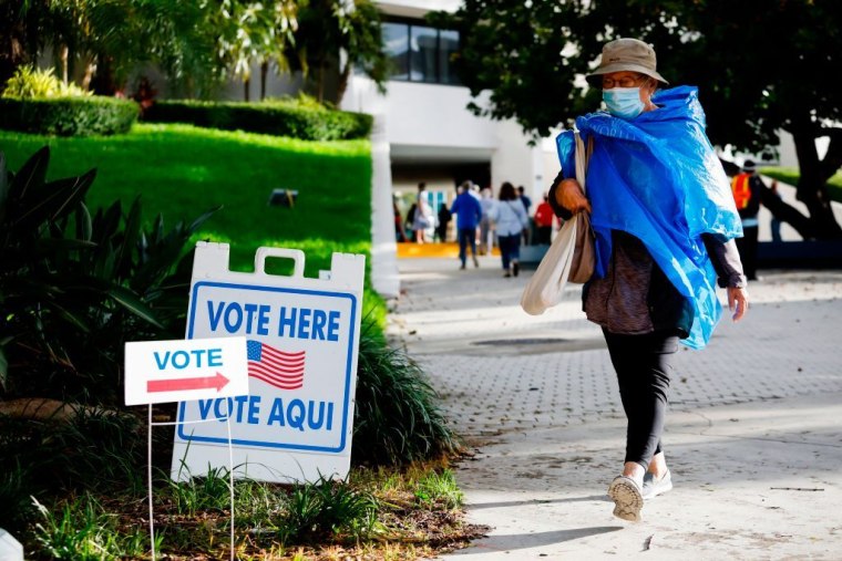Una mujer pasa por delante de un cartel de Vote Here (Vote aquí) en el Ayuntamiento de Miami Beach, Florida, el 19 de octubre de 2020.