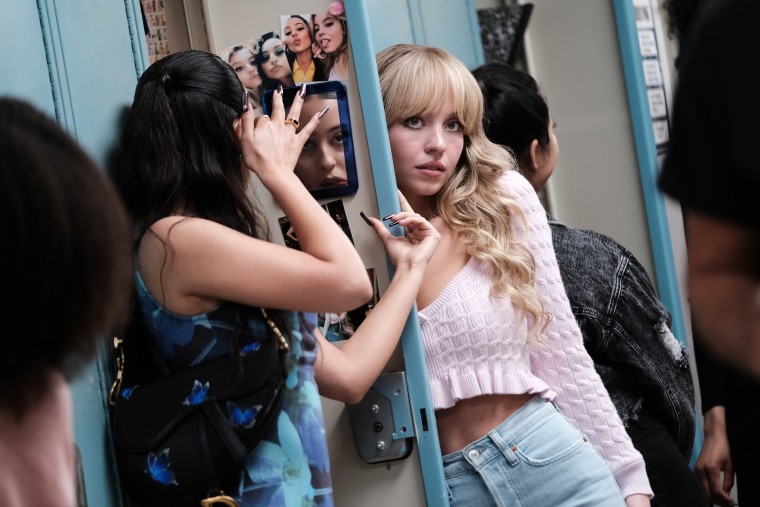 Cassie tries to catch the attention of Nate, Maddy's ex-boyfriend, while Maddy looks in the mirror next to her. 