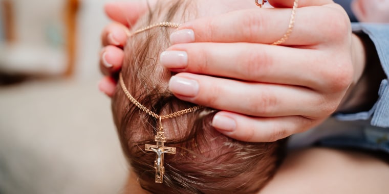 baby with a golden cross on a chain on the head. Christian faith.