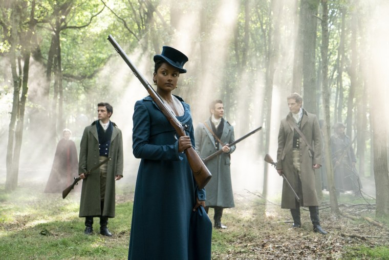 Kate holds a gun in her hand and Anthony stands in the background alongside brother Benedict Bridgerton, played by Luke Thompson, and new co-star Rupert Young, who plays Jack.