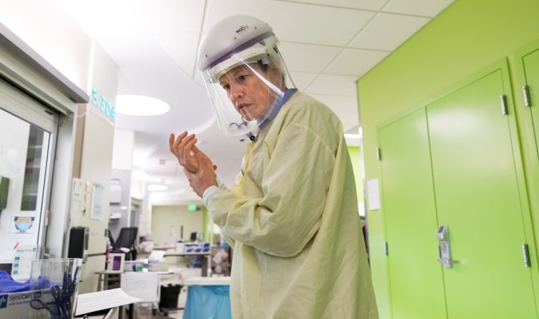 Wearing a controlled air purifying respirator, Dr. John K. McGuire prepares to enter a patient’s room at at Seattle Children’s Hospital on Jan. 28, 2022.