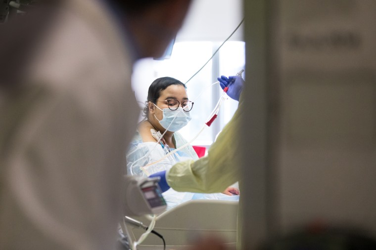Katherine Abud, 17, gets settled in her new room in the pediatric intensive care unit as medical workers bustle all around her.