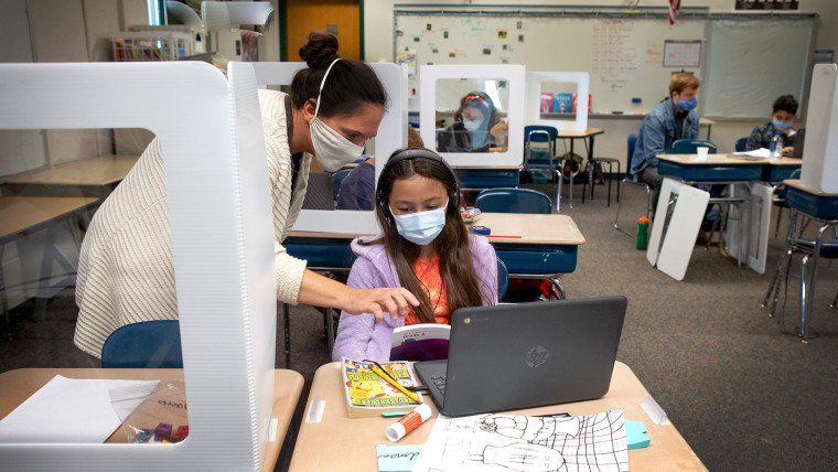 Una maestra de quinto grado ayuda a una estudiante con una lección en la computadora durante la clase.