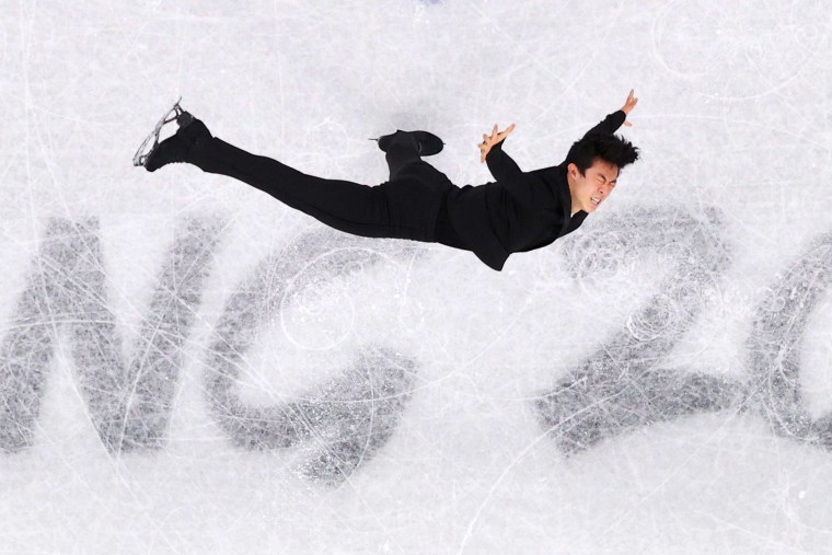 Figure Skating - Beijing 2022 Winter Olympics Day 4 - Nathan Chen in all black waves his arms with one leg in the air.