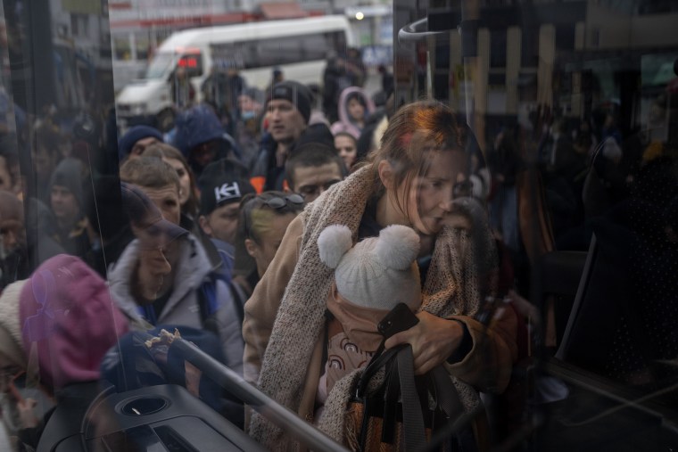 A woman holds her baby as she gets on a bus