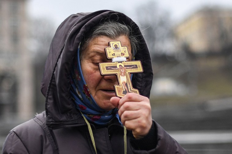 A religious woman holds a cross as she prays