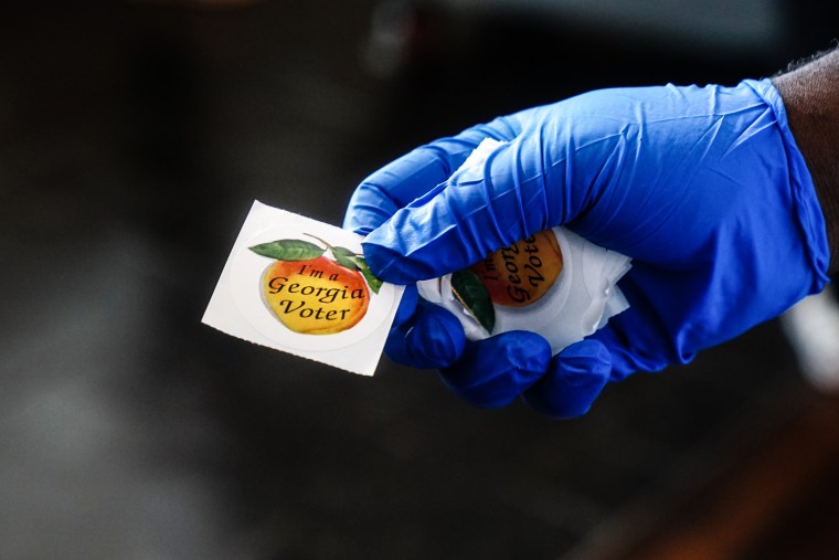 A polling place worker holds an "I'm a Georgia Voter" sticker to hand to a voter on June 9, 2020 in Atlanta.