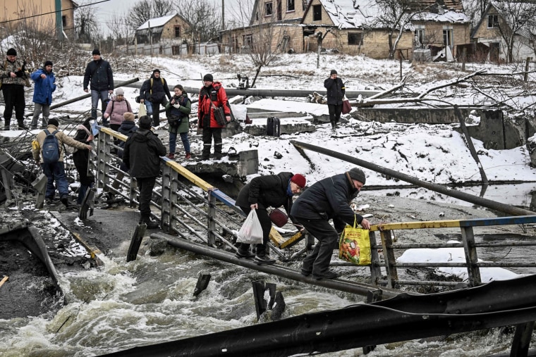 Civilians cross a river on a blown up bridge on Kyiv's northern front on March 1, 2022