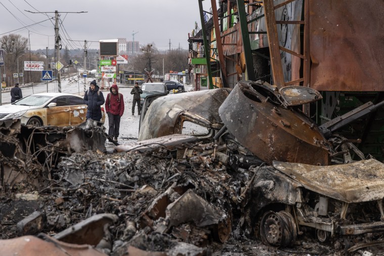 Image: People walk past a destroyed Russian military vehicle at a frontline position on March 3, 2022 in Irpin, Ukraine.