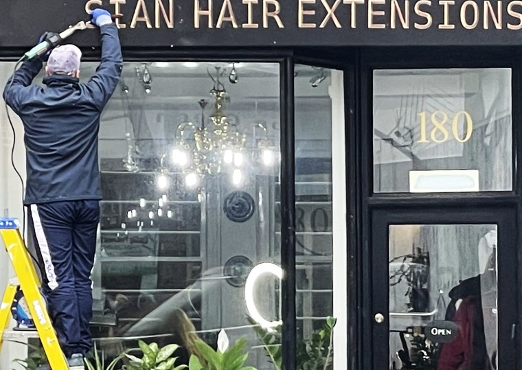 A man on a ladder removes the word “Russian” from the sign above  what the was until now the “Russian Hair Extensions” salon in London’s exclusive Kensington neighborhood.