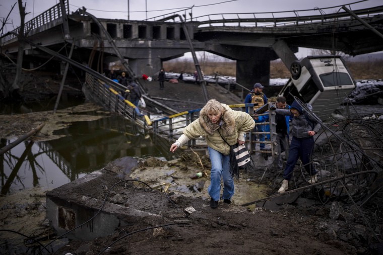 A woman runs as she flees with her family across a destroyed bridge in the outskirts of Kyiv, Ukraine on Wednesday, March 2.
