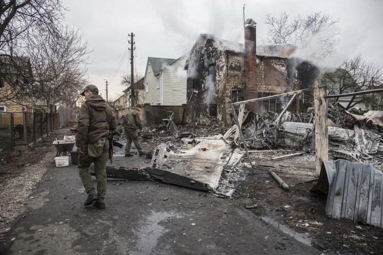 Ukrainian servicemen walk at fragments of a downed aircraft seen in in Kyiv, Ukraine, Friday, Feb. 25, 2022.