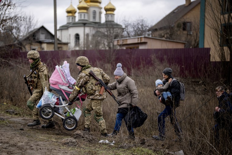 Ukrainian soldiers help a fleeing family crossing the Irpin river in the outskirts of Kyiv, Ukraine on Saturday, March 5.