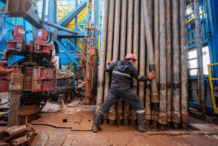 Image: A worker moves drilling pipes at the Gazprom PJSC gas drilling rig in the a gas field near Irkutsk, Russia, on April 7, 2021.