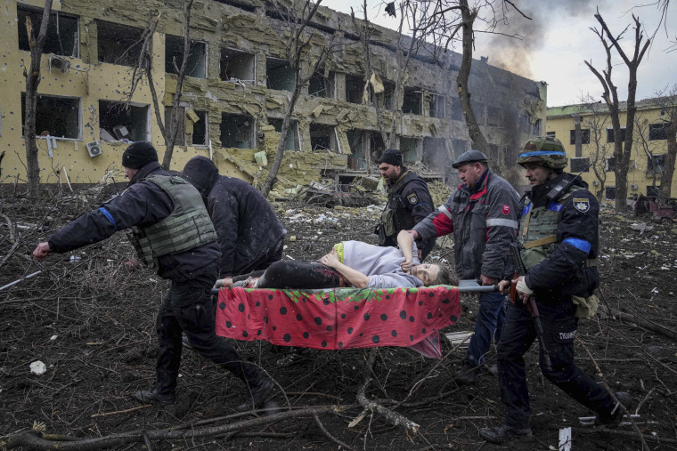Emergency workers and volunteers carry an injured pregnant woman from a maternity hospital that was shelled by Russian forces in Mariupol on Wednesday.