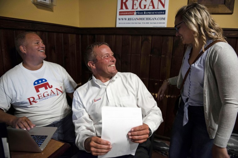 Robert Regan, center, welcomes a friend to his election watch party on Aug. 7, 2018, in Belmont, Mich.