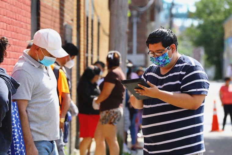 Census 2020 field organizer Jeffrey Tellez, right, interviews a resident in the food pantry line at the Chelsea Collaborative in Chelsea, Mass. to attempt to get an accurate count on June 4, 2020.