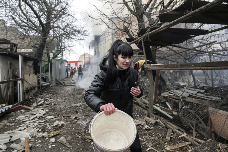 A woman walks past the debris in the aftermath of Russian shelling, in Mariupol, Ukraine, on Feb. 24.