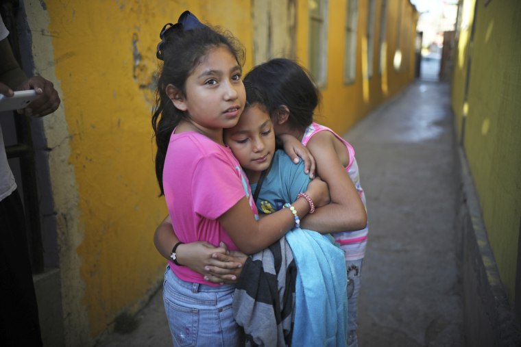 A Honduran girl is hugged by friends