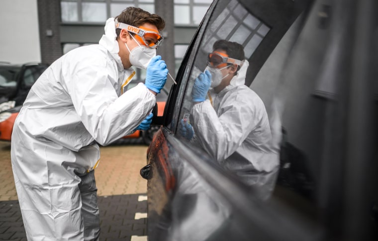 A staff member takes a swab from a patient sitting in a car for a PCR test for coronavirus outside a doctor's office in Lower Saxony, Laatzen, Germany on March 14, 2022.