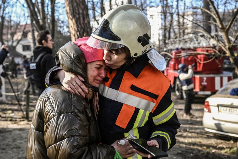 Un secouriste réconforte un résident évacué devant un immeuble en feu à Kiev le 15 mars 2022.