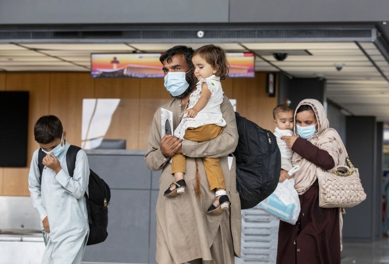 Families evacuated from Kabul walk through the airport