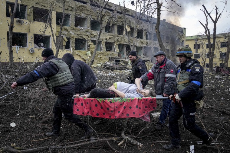 Ukrainian emergency employees and volunteers carry an injured pregnant woman from a maternity hospital destroyed in shelling. 