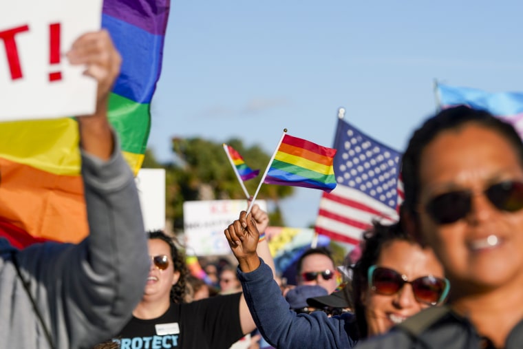Marchers wave flags and signs as they walk at the St. Pete Pier in St. Petersburg, Fla., on March 12, 2022, to protest the controversial "Don't say gay" bill passed by Florida's Republican-led legislature.