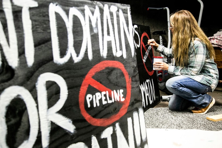 Karmin McShane paints a sign in opposition to a carbon capture and sequestration pipeline on Dec. 14, 2021, in Linn County, Iowa.