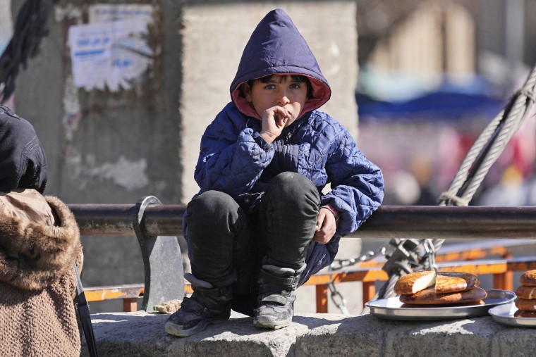 A boy selling bread sits