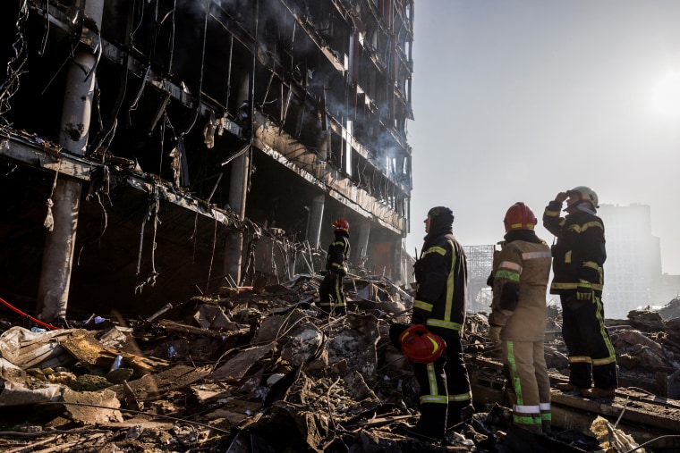 Rescue workers stand at the site of a bombing at a shopping center in Kyiv on March 21, 2022.