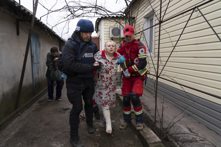 Associated Press photographer Evgeniy Maloletka helps a paramedic to transport a woman injured during shelling in Mariupol. 