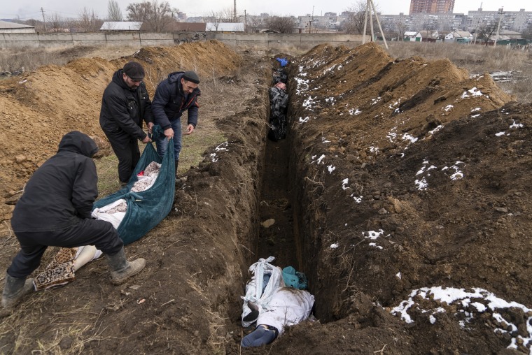 Dead bodies are placed into a mass grave on the outskirts of Mariupol after it became impossible for most people to bury their dead individually because of heavy Russian shelling. 
