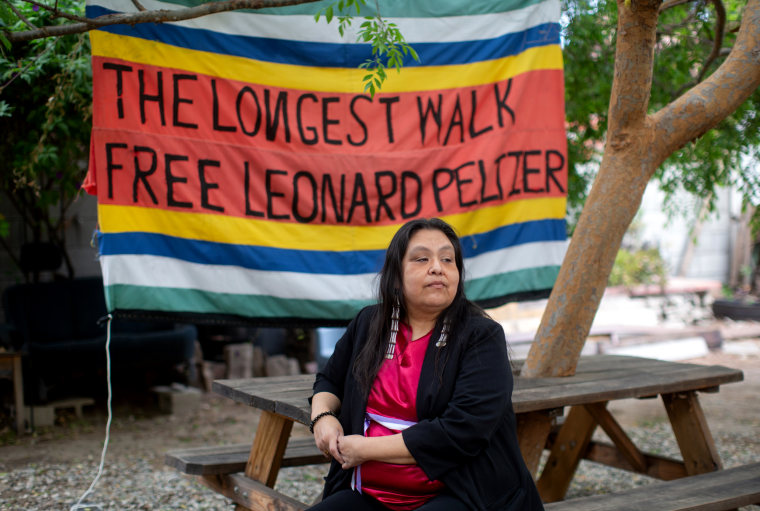 Image: Kathy Peltier, the daughter of Leonard Peltier, in Burbank, Calif., on March 17, 2022. The banner (reads: "The Longest Walk, Free Leonard Peltier") was made for a march of several hundred Native American activists and supporters from San Francisco to Washington, D.C., in 1978.