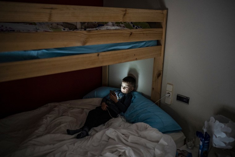 Maxym Batrak, 5 ans, de Brovary, Ukraine, regarde un téléphone dans une maison du village de Guissona, Lleida, Espagne, le 22 mars 2022.