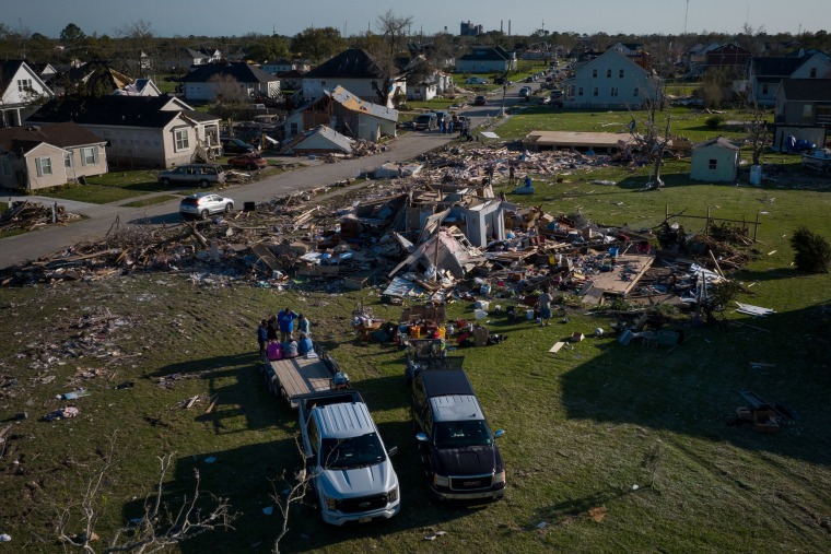 A family holds hands as they pray outside their destroyed home in the aftermath of a tornado in Arabi, Louisiana, on Wednesday, March 23, 2022.