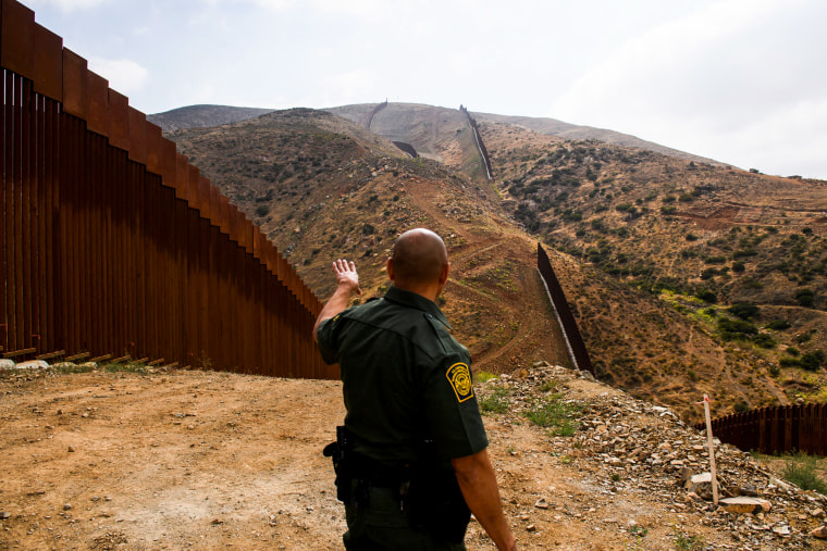A U.S. Border Patrol agent shows an incomplete section of the new steel bollard-style border wall on a hillside along the US-Mexico border between San Diego and Tijuana on May 10, 2021, in the Otay Mesa area of San Diego County, Calif.
