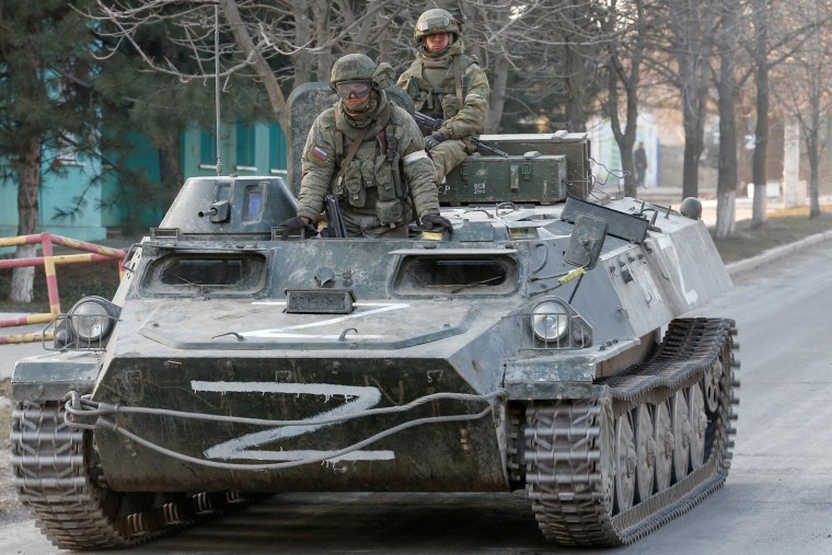 Image: Service members of pro-Russian troops are seen atop of an armoured vehicle in Dokuchaievsk