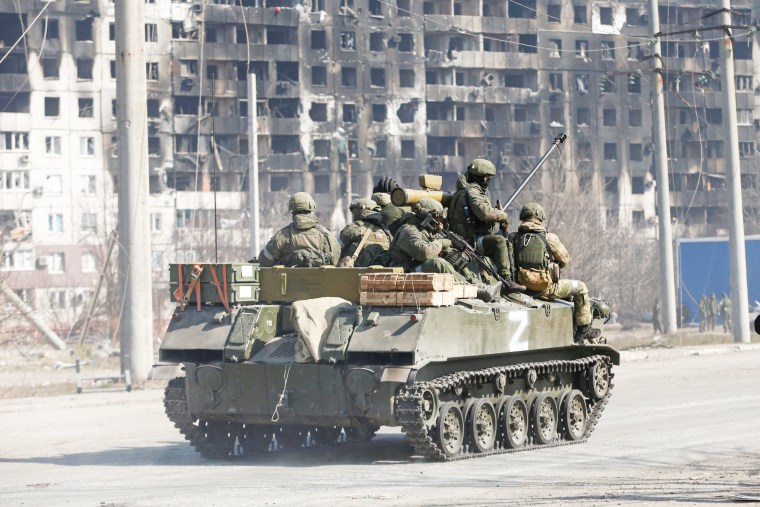 Service members of pro-Russian troops are seen atop of an armoured vehicle