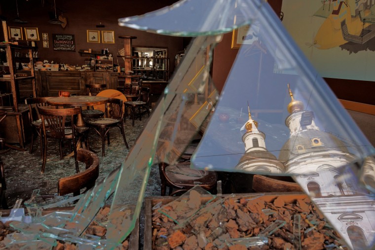 Image: The Assumption Cathedral is reflected in shards of broken window of a cafe house that was damaged during shelling in central Kharkiv