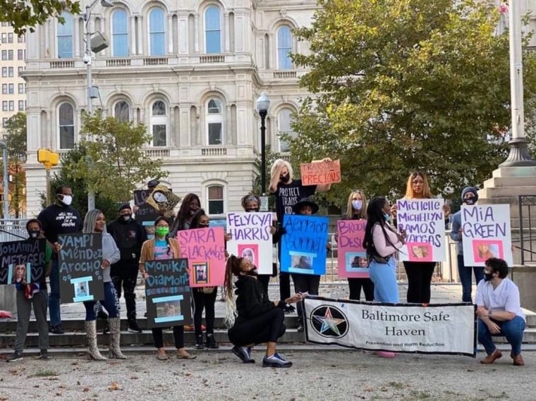 Miembros de Baltimore Safe Haven sostienen los fotos y los nombres de las personas trans que fueron asesinadas en 2020.
