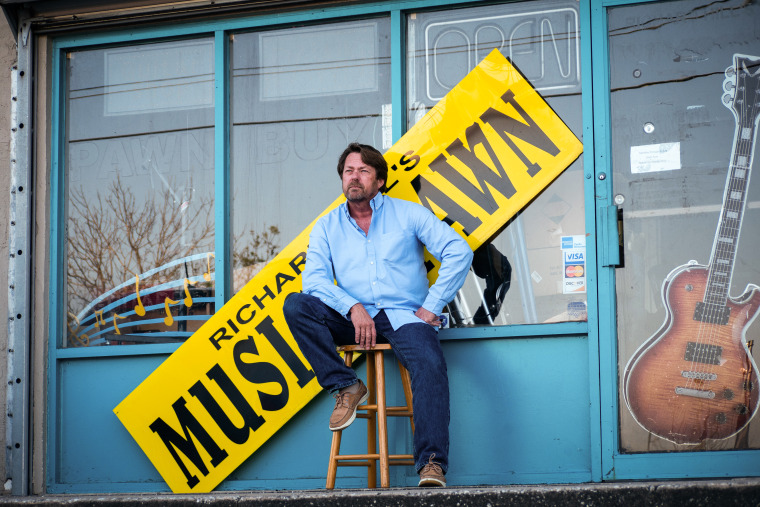 Richard Hill sits in front of his pawn shop, which is now closed for business, in South Daytona, Florida.