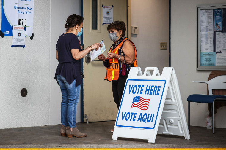 A poll worker speaks with a voter at the entrance to a polling station on Election Day on Nov. 2, 2021 in Miami Beach, Fla.