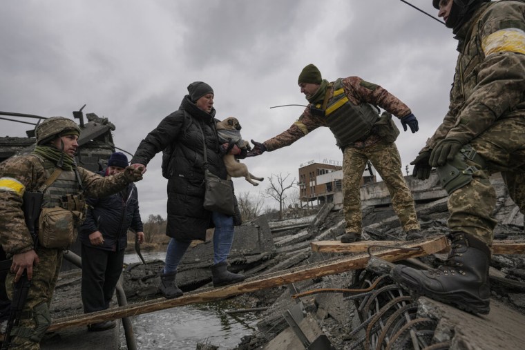 Militares ucranianos ayudan a una mujer y su perro pequeño a cruzar el río Irpin, para escapar de la ciudad del mismo nombre, en Ucrania, el sábado 5 de marzo de 2022. 