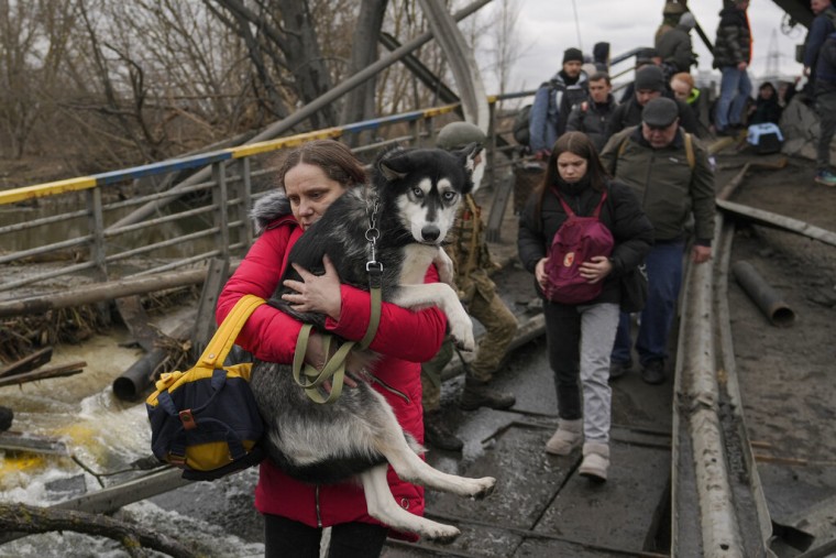 Una mujer sostiene a su perro mientras cruza el río Irpin para huir de la ciudad de igual nombre en Ucrania, el sábado 5 de marzo de 2022.