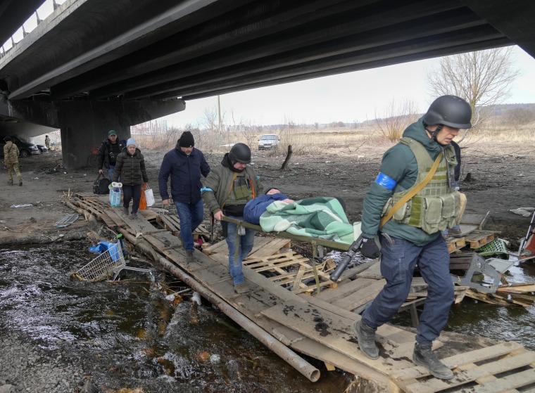 Soldados ucranianos pasan por un camino improvisado bajo un puente destruido mientras evacuan a un anciano residente en Irpin, al noroeste de Kiev, el sábado 12 de marzo de 2022.