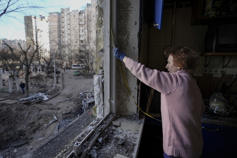 Una mujer mide una ventana antes de cubrirla con plástico el lunes 21 de marzo de 2022, en un edificio dañado por un ataque el día anterior, en Kiev, Ucrania.
