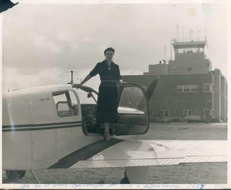 Una mujer en vestido se asoma desde la cabina de una aeronave